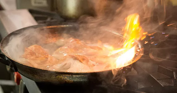 A pan flares up while sauteing chicken at ICE Los Angeles campus