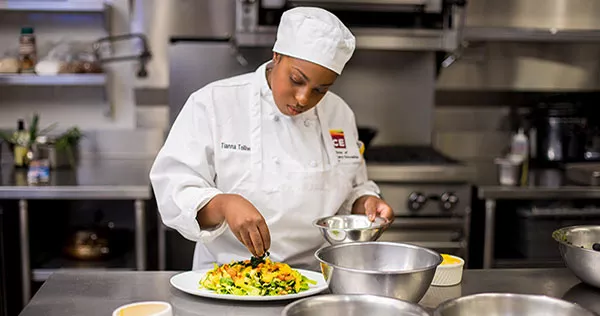 A Plant-Based Culinary Arts student at the ICE Los Angeles campus prepares a colorful salad