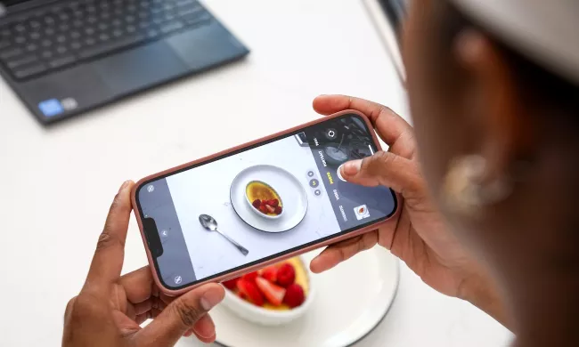 A student takes a photo of a creme brulee on their phone