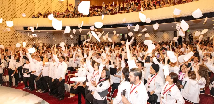 Graduates at the ICE LA 2023 commencement ceremony throw their toques in the air in celebration