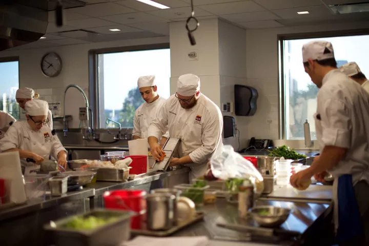 Students in white chef coats work in an ICE kitchen