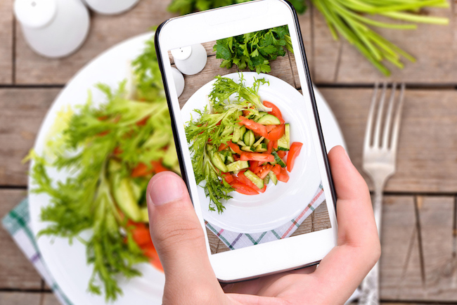 A student takes a photo on their phone of a plated salad