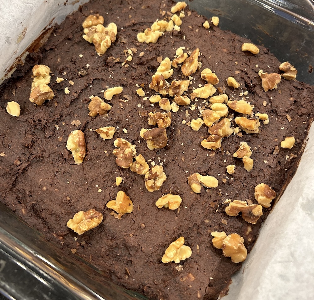 Brownies topped with walnuts sit in a glass baking dish