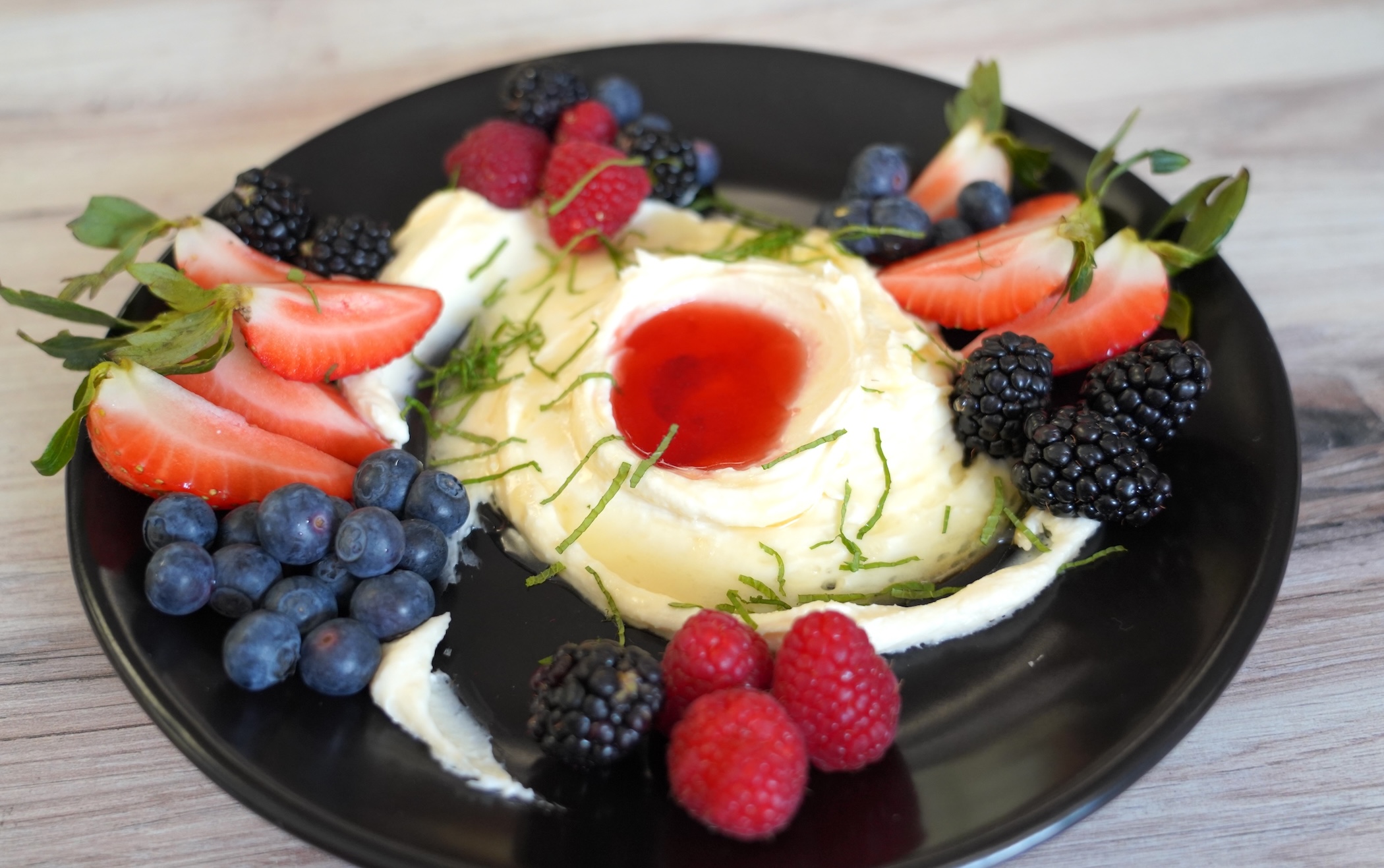 Whipped feta dip on a black plate surrounded by food
