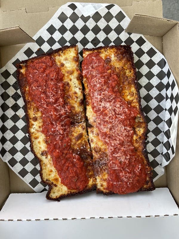 two rectangular Detroit pizzas on a checkerboard napking