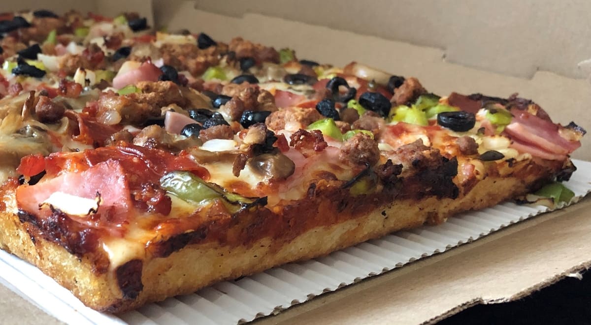 Square Detroit-style pizza with crispy edges and veggie toppings