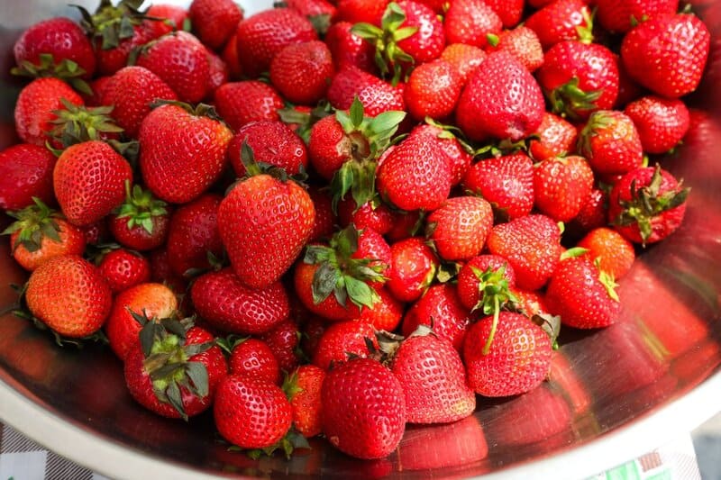 Red, ripe strawberries piled high in silver mixing bowl