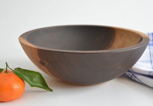 Wooden bowl staged with an orange and plaid towel.