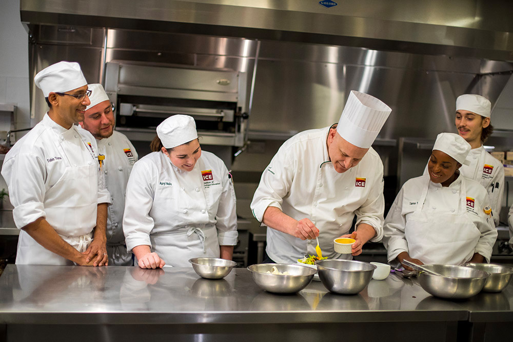Chef demonstrating technique to students in professional kitchen