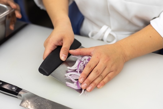 ICE student chopping purple onions in the kitchen. 