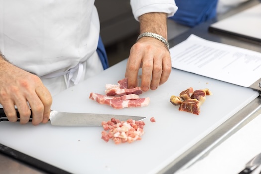 ICE chef cutting proteins on a cutting board.
