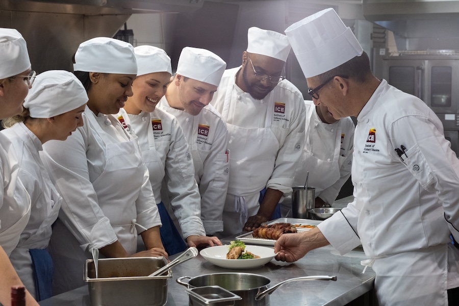 Students and Chef-Instructor Roger in a kitchen classroom at the ICE NYC campus.