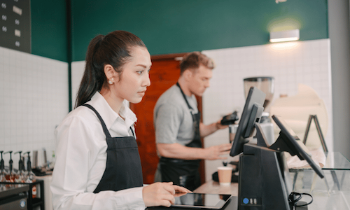 A barista using a modern restaurant POS system to take an order.