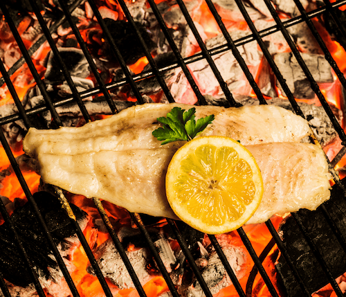 Grilled fish garnished with a lemon slice, showcasing a delicious and appetizing meal.