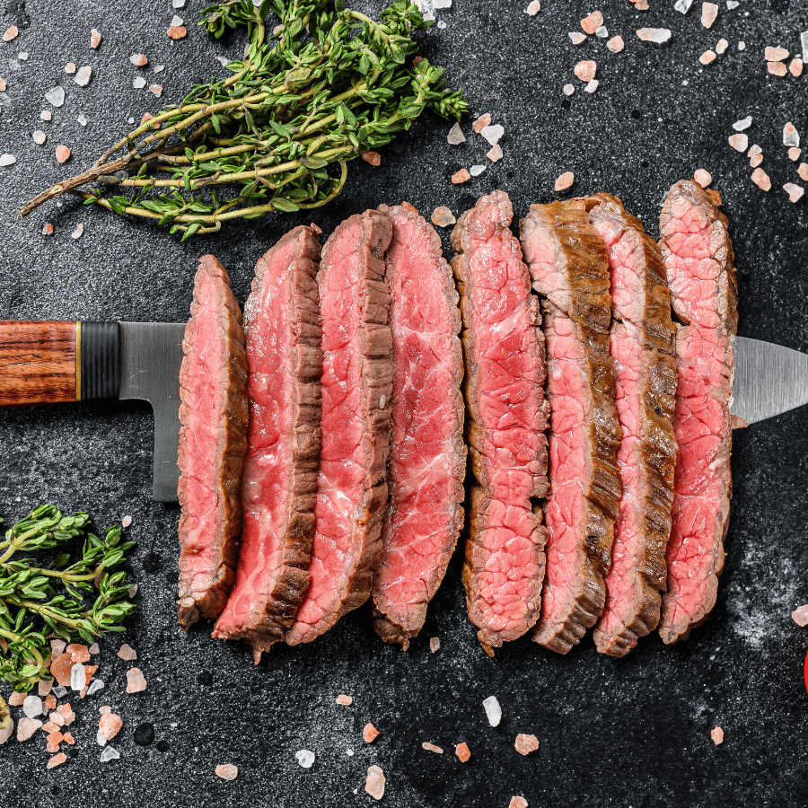 An image of a rare-cooked sliced steak on a knife.