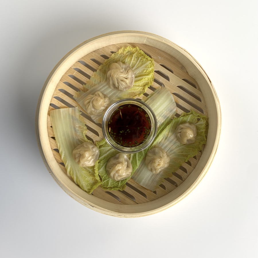 Four Xiao long bao, one of the many types of Chinese dumplings, sit in a bamboo basket