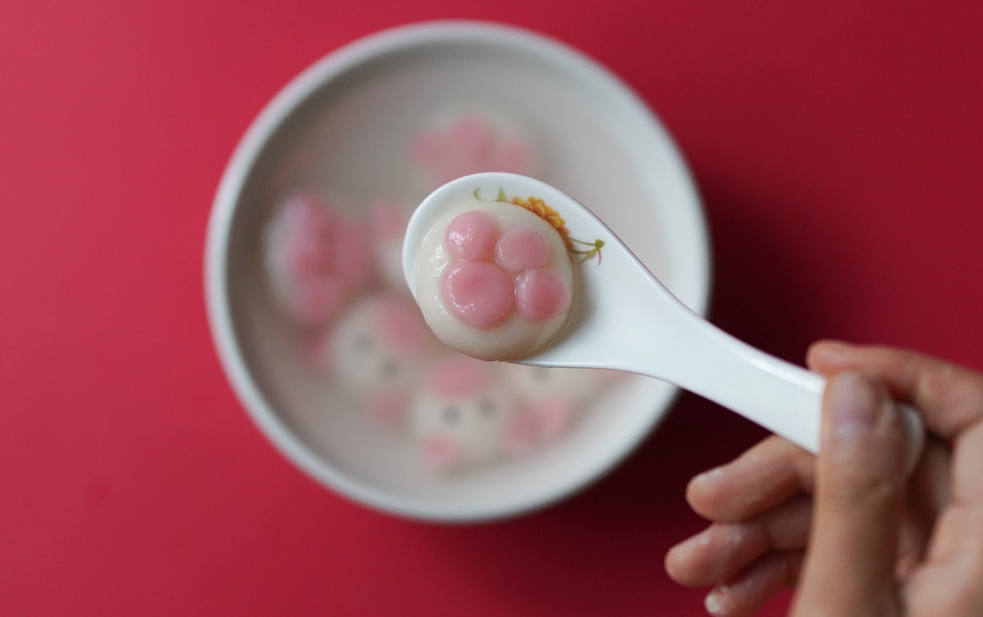A paw print shaped tang yuan sits on a white spoon