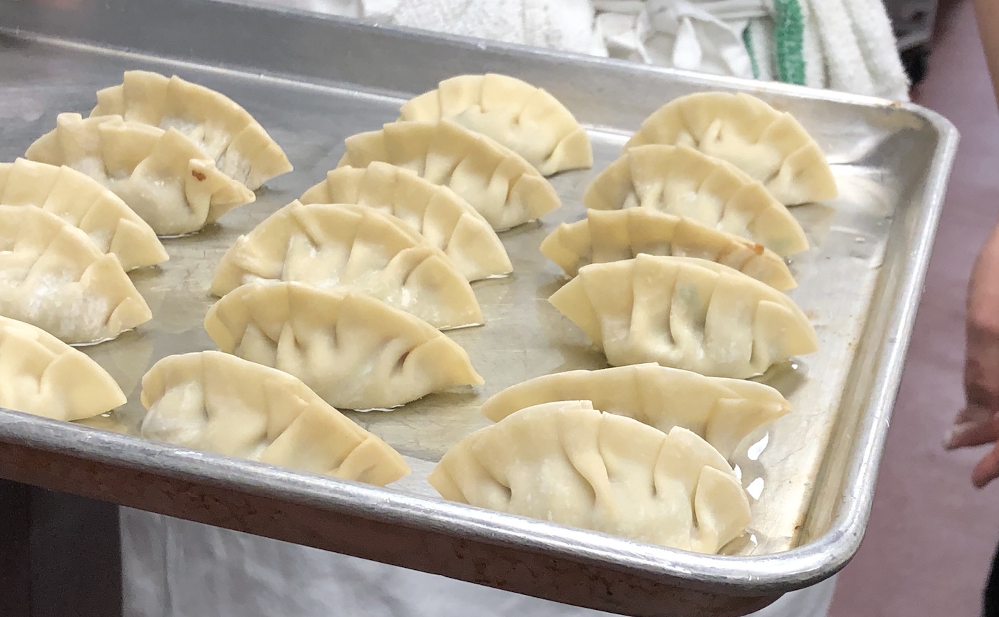 Uncooked braided Chinese dumplings sit on a metal tray