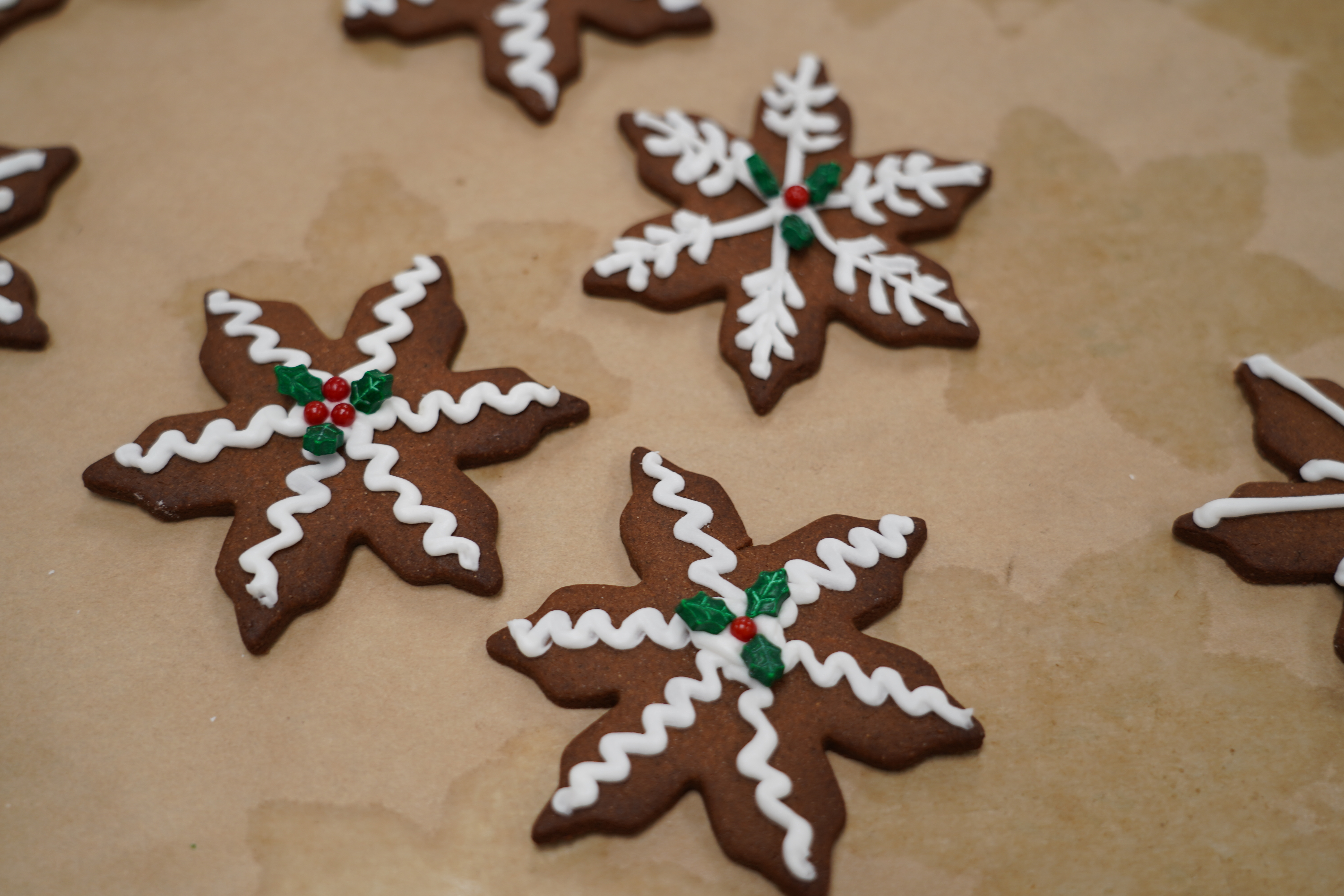 Gingerbread cookies shaped like snowflakes sit on a parchment paper sheet