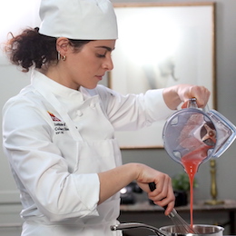 ICE alumni Gianna Longo pours a sauce into a pan for ICE's plant based culinary program