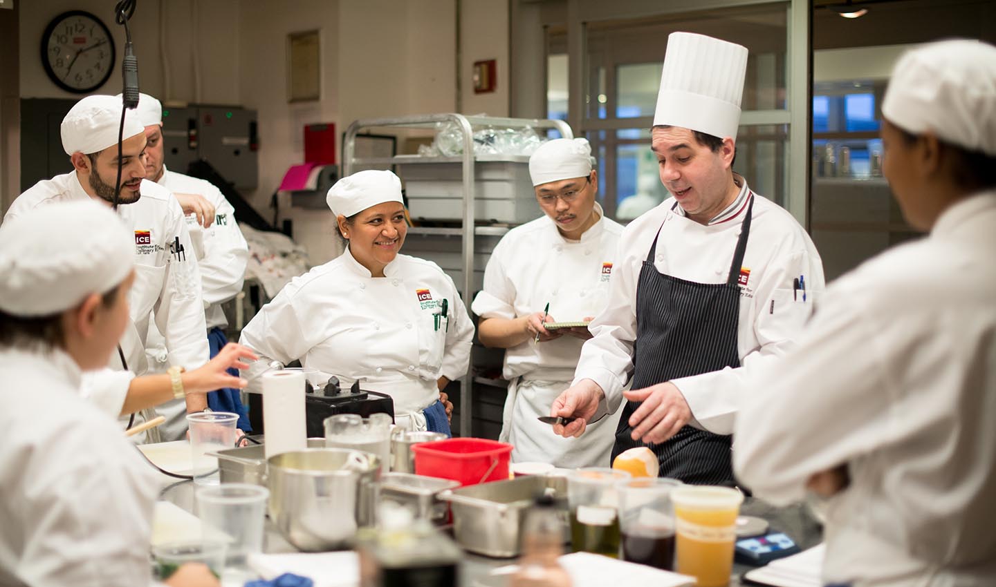 An ICE chef-instructor demonstrates a technique to a room full of students in ICE's Culinary Arts campus programs. 