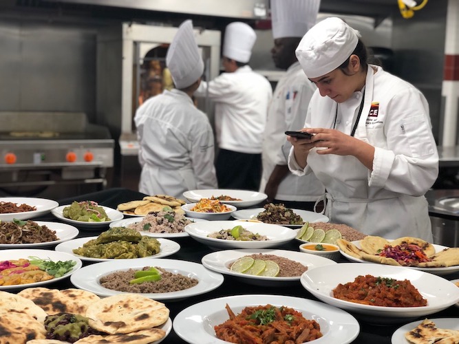 A Culinary school student photographs her class's spread of Latin food at Institute of Culinary Education