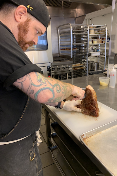 Chef Chris Arturo prepping a steak in the ICE kitchen