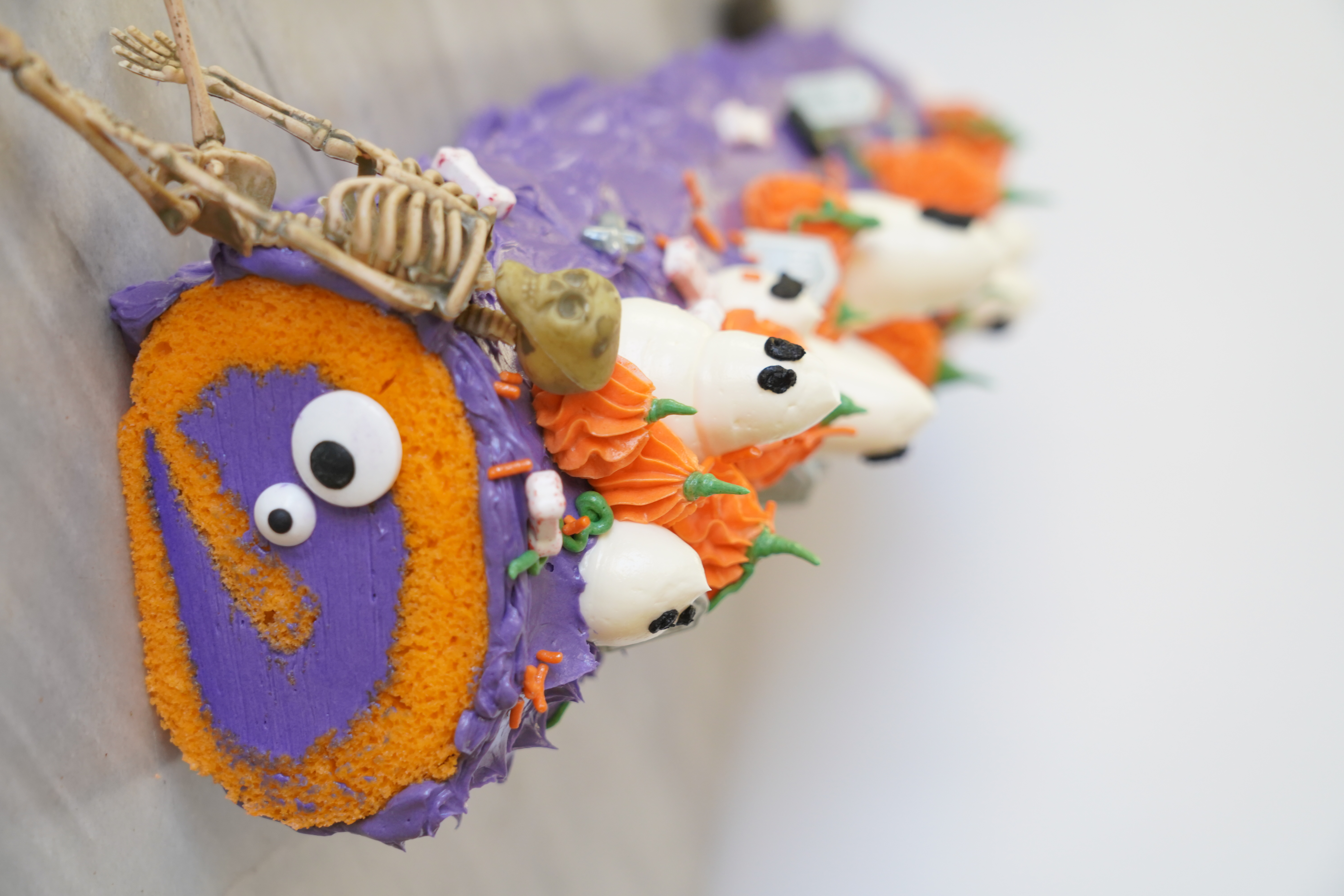 An orange and purple cake decorated with Halloween sprinkles on a white plate