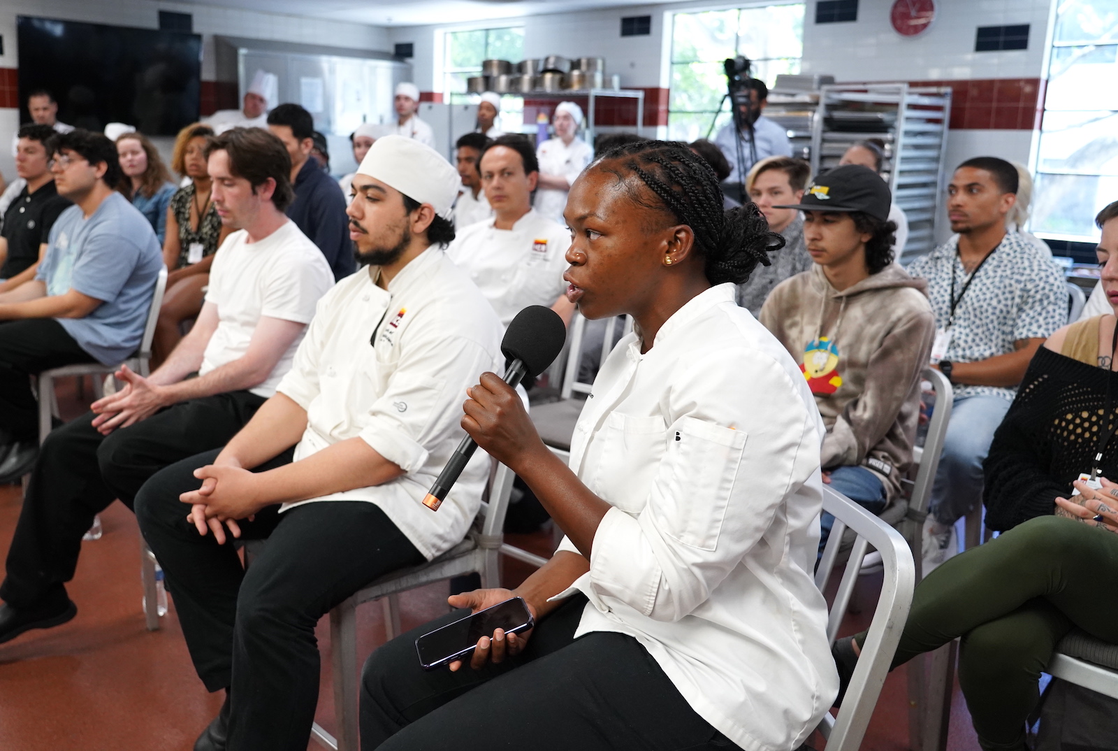 An ICE student holds a microphone and asks Chef Neal Fraser a question