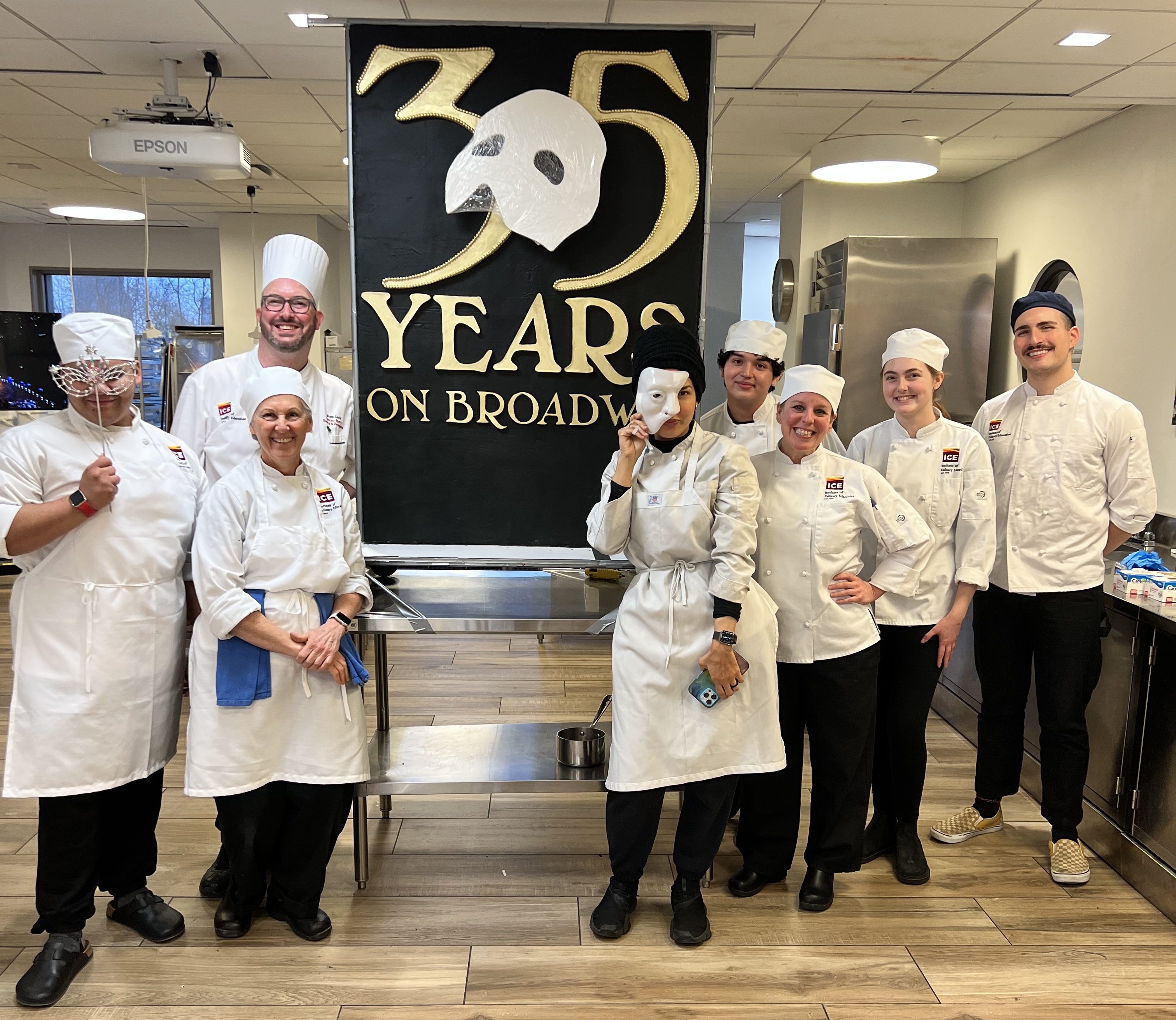 Chef Jürgen and student volunteers stand next to the completed cake