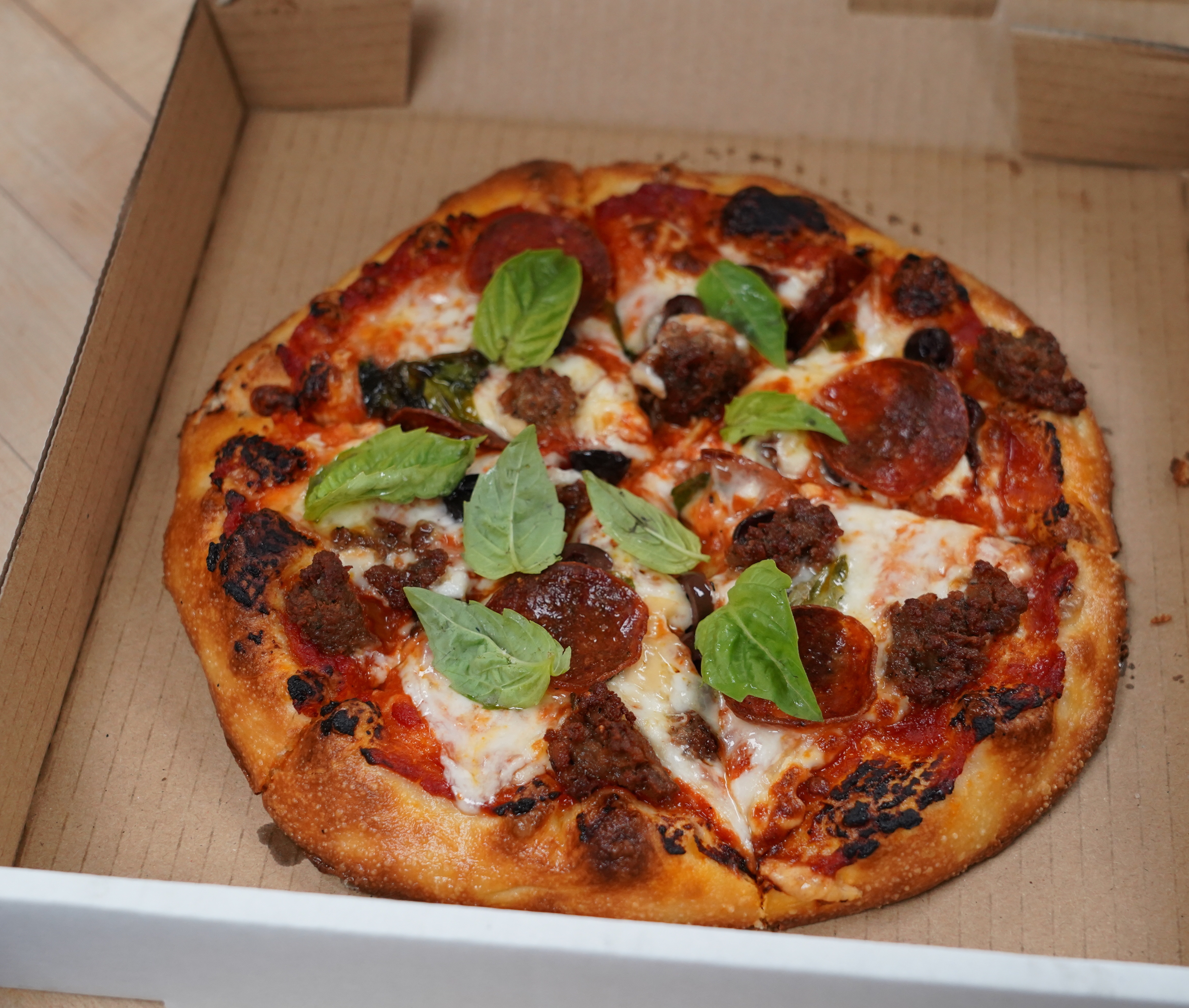 A pizza sits in a brown cardboard box