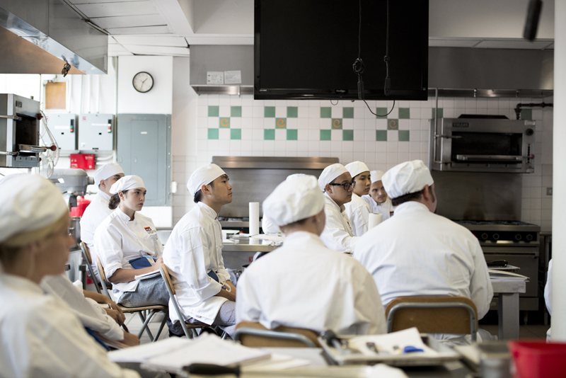 Culinary students listening to chef instructor at school in New York