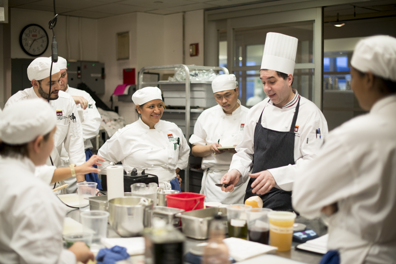 Culinary students listening to chef instructor at school in New York