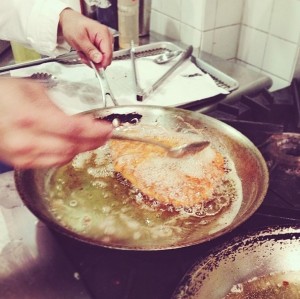 Basting a fried cutlet to achieve the perfect golden brown crust.