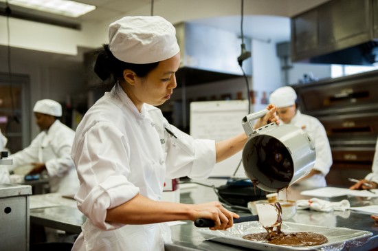 Culinary student pouring chocolate into a mold