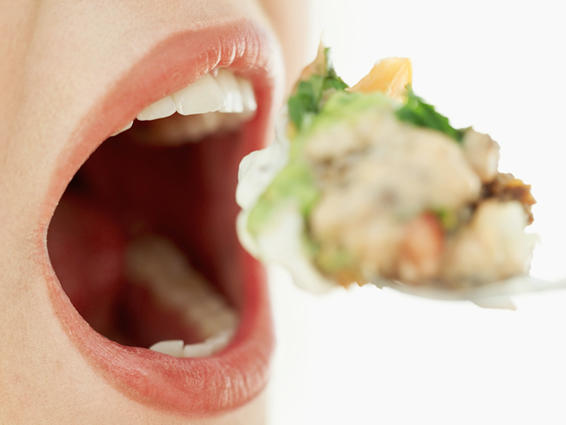 person taking a bite of food with mouth open wide