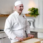 ICE alum Alex Terepka smiles while rolling out dough