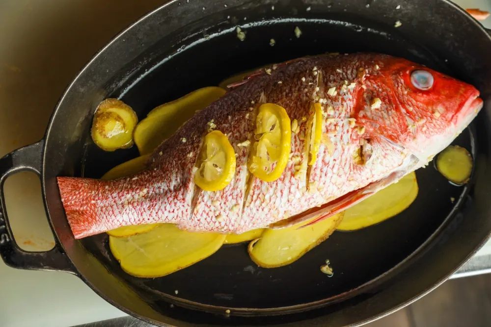 Whole red snapper in pan with aromatics