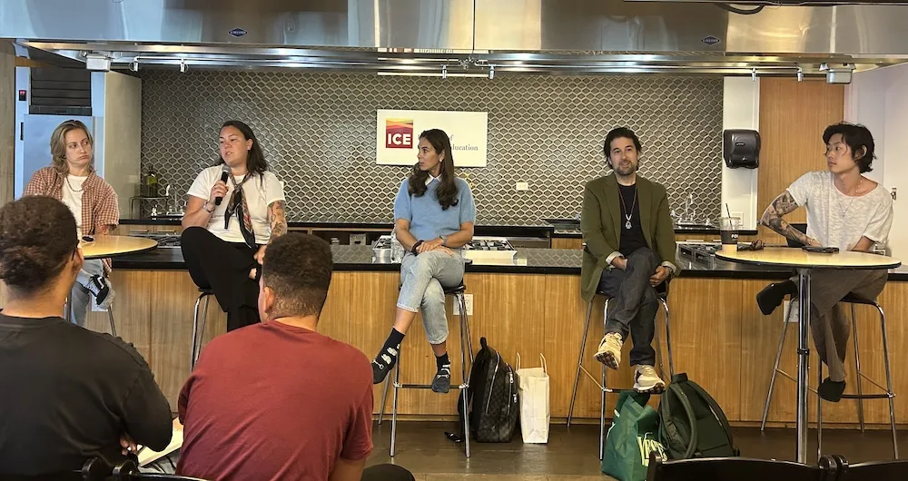 5 panelists sit on chairs in a row