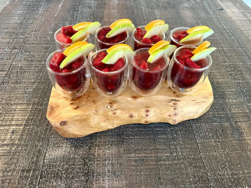 8 glasses of pineapple hibiscus punch sangria arranged on a wooden board.