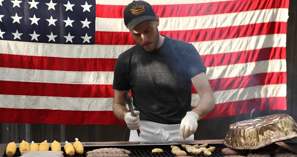 ICE alum James Durrazo on the grill with corn and meat in front of an American flag. 