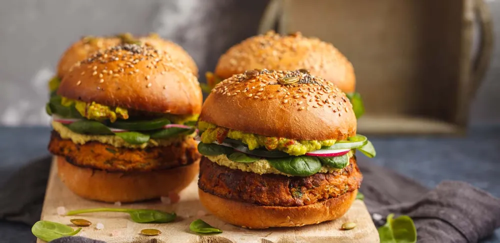 Vegan burgers sit on a wooden cutting board