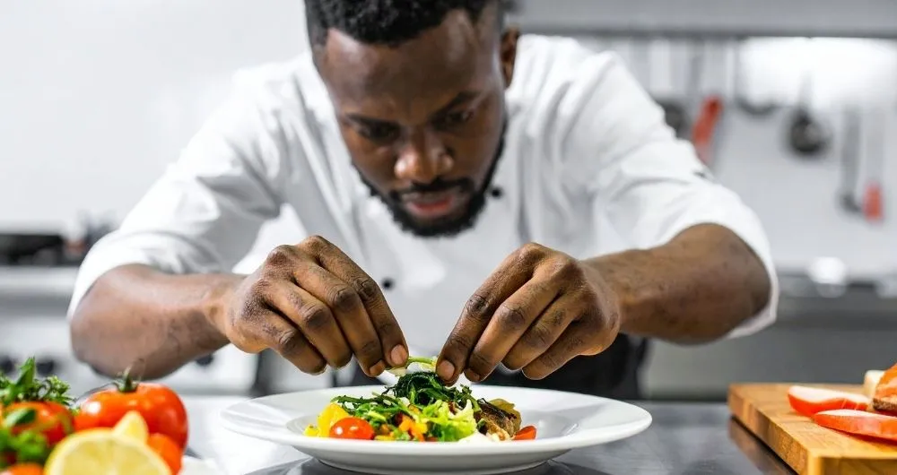 A chef skillfully arranges food on a plate, showcasing culinary expertise and attention to detail.