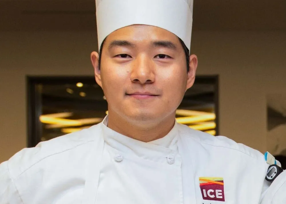 chef bobby yoon in chef's toque and culinary school jacket