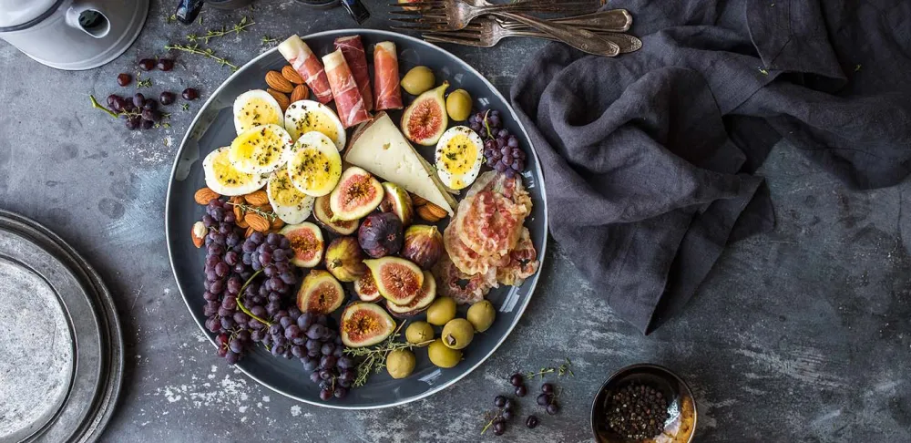 Bowl of fruits nuts cheese meat and eggs