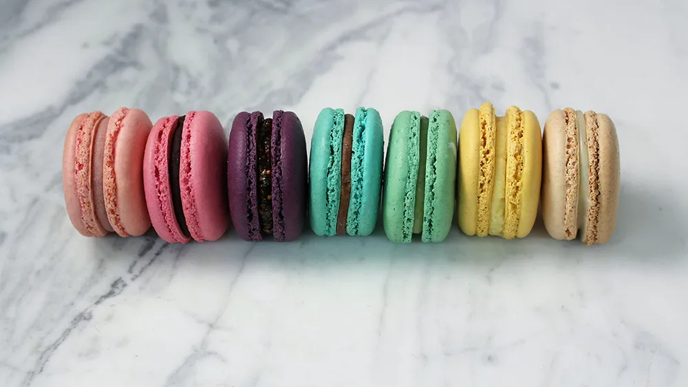 Colorful macarons in a row on a marble counter