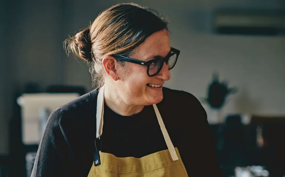 Chef Missy Robbins makes ravioli pasta wearing black sweater and mustard apron