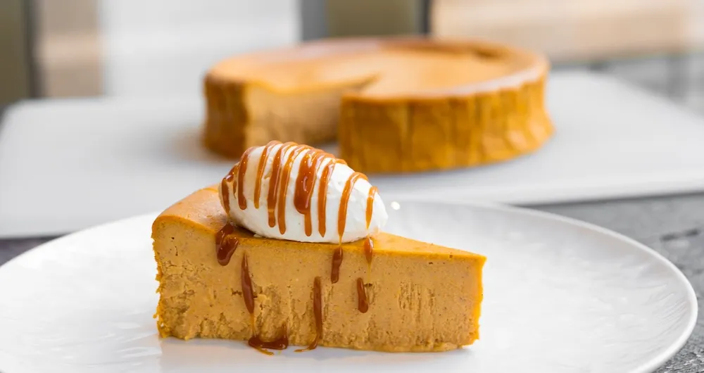 Slice of Pumpkin Basque Cheesecake topped with whipped cream and caramel