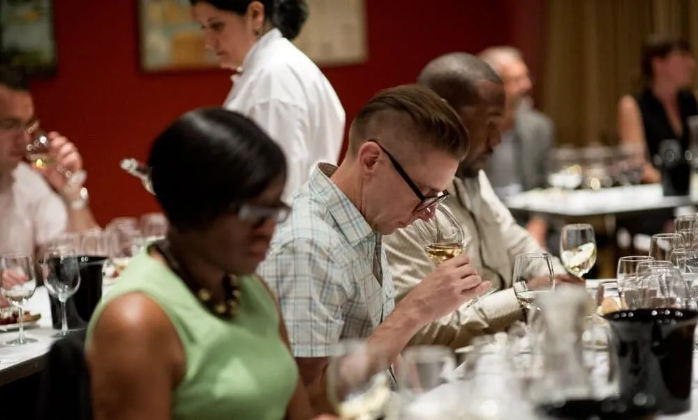 Wine student assessing aroma of red wine in glass at recreational wine class.