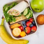 An overhead view of a healthy lunch box meal layout on a light textured background.